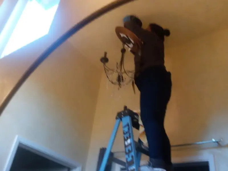 Electrician installing a chandelier in a Waukee residence